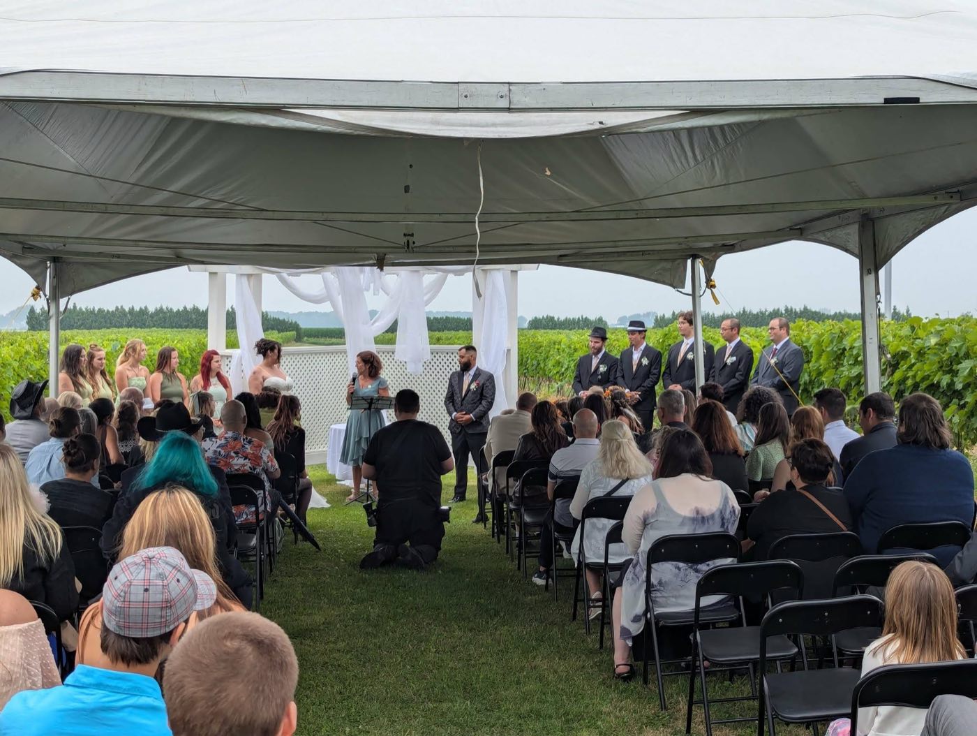 Cérémonie de mariage bilingue sous un chapiteau devant un vignoble, animée par Isabelle Ferland.